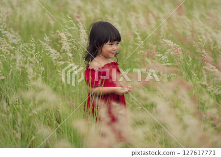 toddler girl in red dress playing grass flower in field toddler girl in red dress playing grass flower in field 127617771