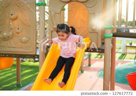 happy toddler baby girl sliding and playing at playground 127617772