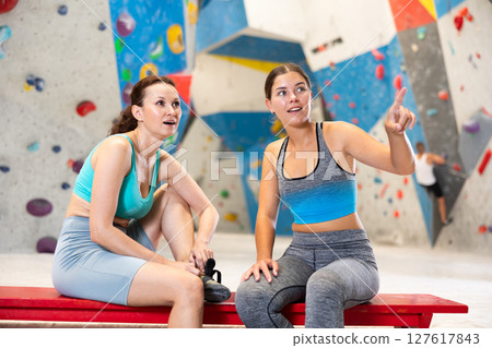 Rest after rock climbing - two friends exchange impressions about training at climbing wall 127617843