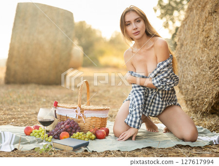 Attractive sexy woman in checked shirt with open neckline posing against background of autumn nature and straw 127617994
