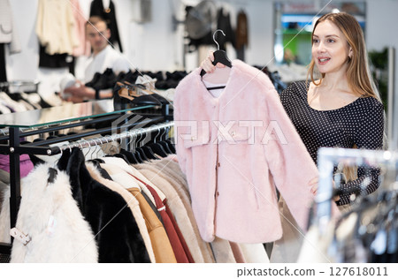 Young woman choosing fur coat in clothing store Young woman choosing fur coat in clothing store 127618011