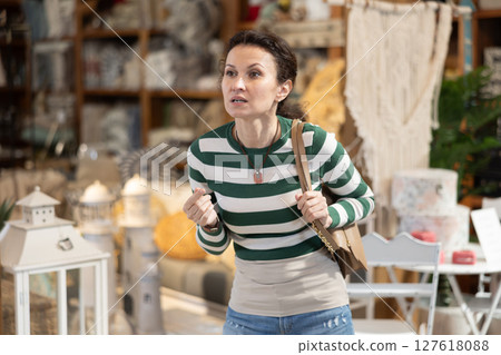 Shopper browses furniture store looking for perfect items for her garden. She carefully examines assortment on display 127618088