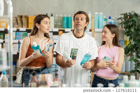 Father, mother and daughter choose toothbrushes together at drugstore Father, mother and daughter choose toothbrushes together at drugstore 127618111