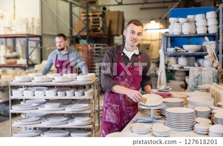 Young man cleaning blanks of ceramic products Young man cleaning blanks of ceramic products 127618201