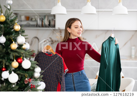 Portrait of attractive woman selecting dress for Christmas celebration 127618219