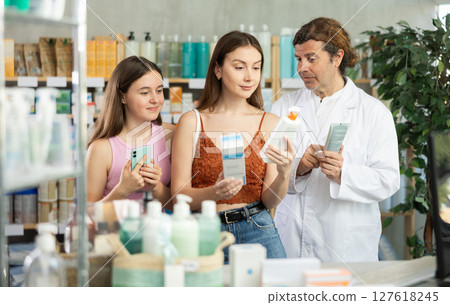 Woman with teen girl choosing and scan QR code cream at pharmacy 127618245