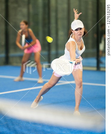 Young and adult women playing doubles tennis 127618295