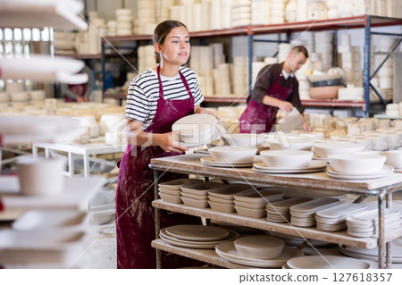Female ceramicist placing handcrafted plates on storage racks Female ceramicist placing handcrafted plates on storage racks 127618357