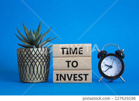 Time to Invest symbol. Concept words Time to Invest on wooden blocks. Beautiful blue background with alarm clock and succulent plant. Business and Time to Invest concept. Copy space 127620286