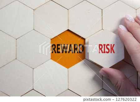 Risk or Reward symbol. Concept word Risk or Reward on wooden comb puzzle. Businessman hand. Beautiful orange background. Business and Risk or Reward concept. Copy space 127620322