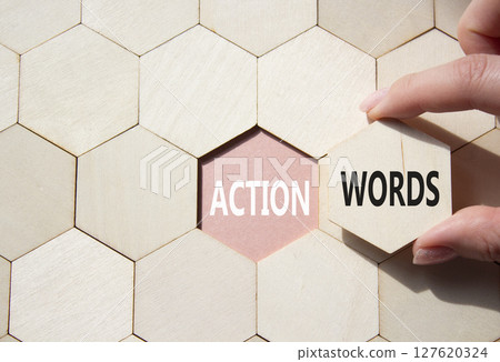 Action or words symbol. Concept word Action or words on wooden comb puzzle. Businessman hand. Beautiful pink background. Business and Action or words concept. Copy space Action or words symbol. Concept word Action or words on wooden comb puzzle. Businessman hand. Beautiful pink background. Business and Action or words concept. Copy space 127620324