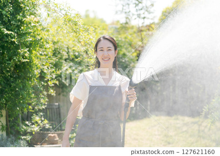 Woman watering the garden Woman watering the garden 127621160