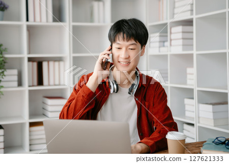 Happy asian business man have the joy of talking on the smartphone, tablet and laptopon the office Happy asian business man have the joy of talking on the smartphone, tablet and laptopon the office 127621333