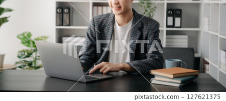 Portrait of young man sitting at his desk in the office 127621375