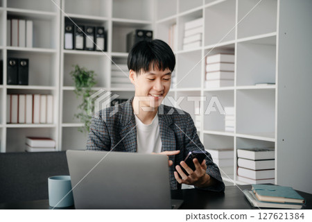 Portrait of young man sitting at his desk in the office 127621384