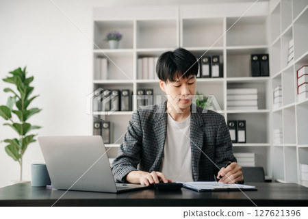 Portrait of young man sitting at his desk in the office 127621396
