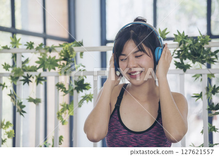 Beautiful woman smile listen music. Yoga woman workout in sportswear sit on yoga mat home fitness workout exercise. Happy beauty women dance on floor use headphone listen to music wellness lifestyle 127621557