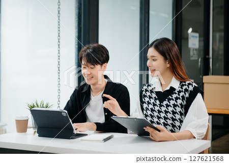 Two Asian businesswoman and man discuss investment project working and planning strategy with tablet laptop computer in office. Two Asian businesswoman and man discuss investment project working and planning strategy with tablet laptop computer in office. 127621568