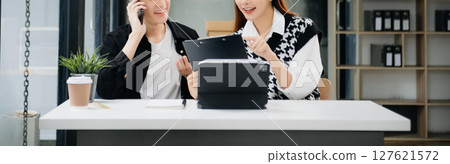 Asian business colleague business presents and explains and using laptop and tablet. Teamwork, financial marketing team,   while sitting in modern office room. 127621572