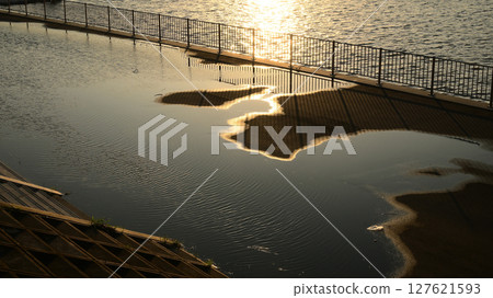 Sunset shining into a puddle 127621593