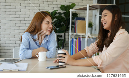 Two pretty best friends forever girlfriend talk, hug and laugh together sitting on sofa in cozy home relax. Happy friendship smile talking together positive emotion in living room joyful lifestyles 127621665