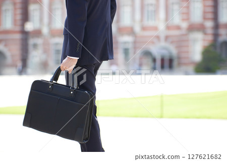 A young businessman in a suit walking through a business district 127621682