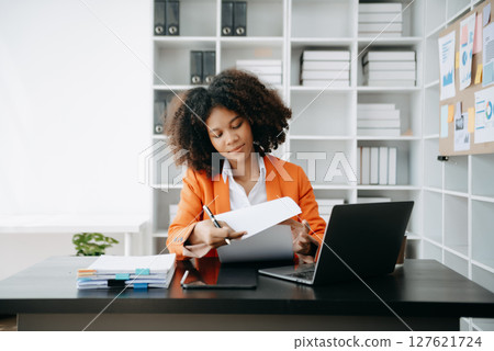 Successful African Businesswoman Analyzing Finance on Tablet and Laptop at modern Office Desk tax, 127621724