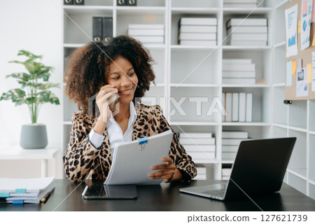 Successful African Businesswoman Analyzing Finance on Tablet and Laptop at modern Office Desk tax, 127621739