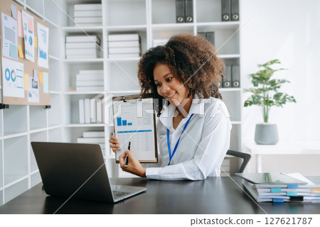Successful African Businesswoman Analyzing Finance on Tablet and Laptop at modern Office Desk tax, 127621787
