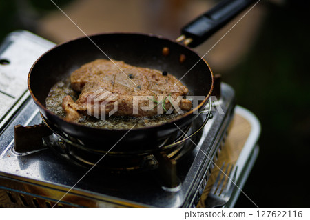 chef cooking beef steak in frying pan on stove in restaurant kitchen 127622116