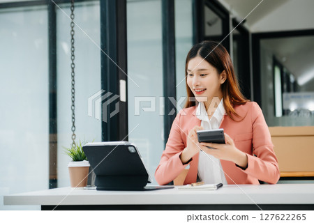 Asian businesswoman working in the office with working notepad, tablet and laptop documents Asian businesswoman working in the office with working notepad, tablet and laptop documents 127622265