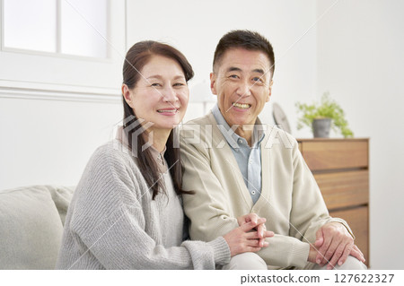 Senior couple portrait looking at camera living room 127622327