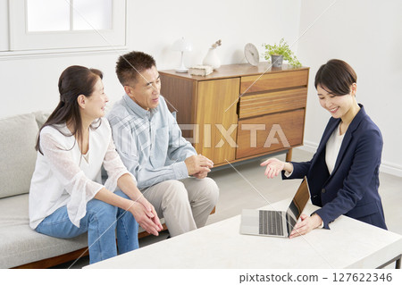 Senior couple talking to a saleswoman in the living room 127622346