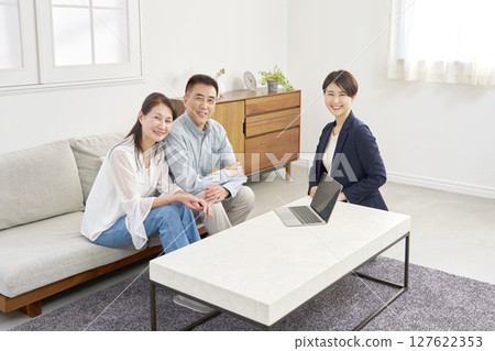 Saleswoman and senior couple portrait looking at camera living room 127622353