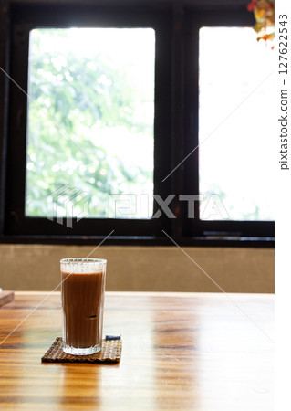Cup of delicious iced chocolate on wooden table background by the window. Cup of delicious iced chocolate on wooden table background by the window. 127622543