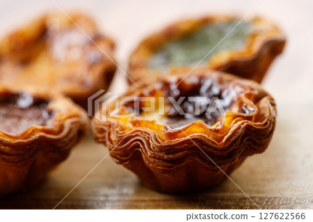 closeup of assorted Portuguese sweet dessert egg tart or Pastel de Nata on wooden board on wooden table. closeup of assorted Portuguese sweet dessert egg tart or Pastel de Nata on wooden board on wooden table. 127622566
