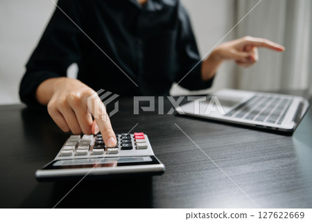 Close up of businesswoman or accountant hand typing laptop working to calculate on desk about cost at office. 127622669