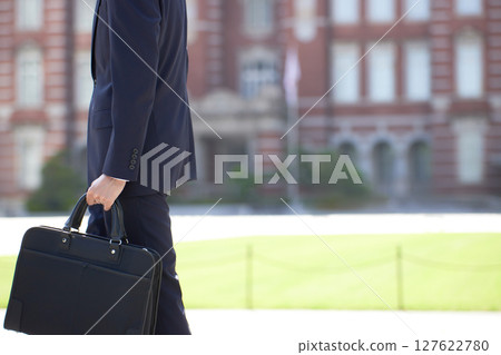 A young businessman in a suit walking through a business district 127622780