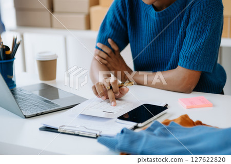 Young woman running online store Startup small business SME, using smartphone or tablet taking receive and checking online purchase shopping order Young woman running online store Startup small business SME, using smartphone or tablet taking receive and checking online purchase shopping order 127622820