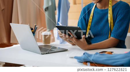 Young woman running online store Startup small business SME, using smartphone or tablet taking receive and checking online purchase shopping order 127622821