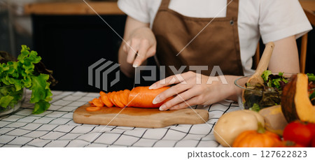 Young Woman cooking dinner has video call conversation in kitchen. Smiling happy female talking with friend using application on computer. 127622823
