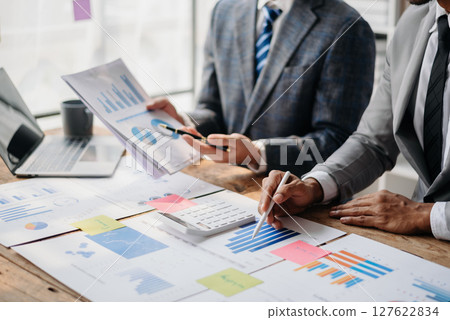 Business People Talking Discussing with financial document data charts and graphs Team business meeting with smart phone and laptop and digital tablet computer 127622834