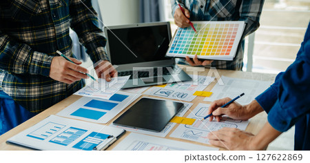 UX developer and ui designer brainstorming about mobile app interface wireframe design with customer breif and color code at modern office. 127622869