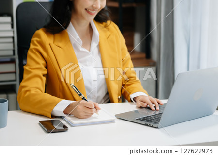 Portrait of female office businesswoman startup daydreaming about her work, startup and working with laptop on office desk in office 127622973