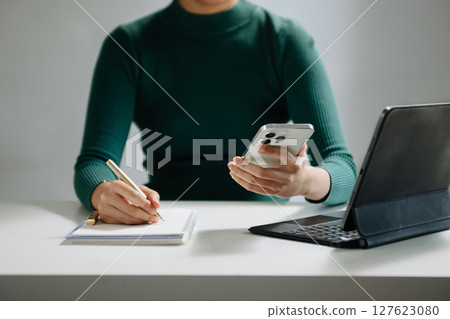 Close-up view of young professional businessman writing his idea concepts on notebook while working on his project 127623080