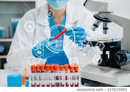 DNA molecule testing concepts. The doctor in a mask examines DNA molecules on the chemical laboratory with virtual icon DNA molecule testing concepts. The doctor in a mask examines DNA molecules on the chemical laboratory with virtual icon 127623093