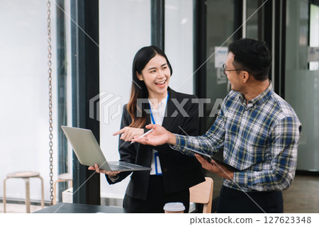 Happy businesspeople while collaborating on a new project in an office. diverse businesspeople using a laptop and tablet 127623348
