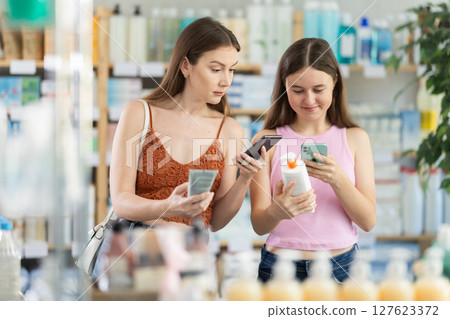 Woman with daughter scanning qr code of cream 127623372