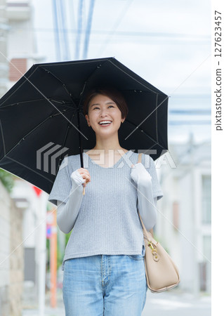拿著遮陽傘的一名微笑的婦女 127623457