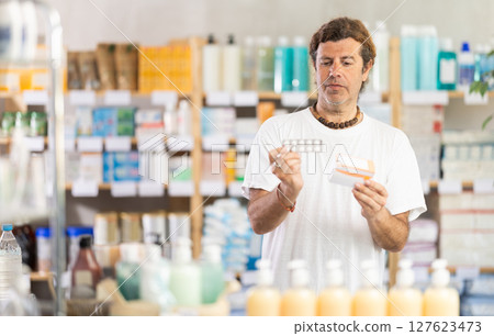 Adult man chooses pills at pharmacy Adult man chooses pills at pharmacy 127623473